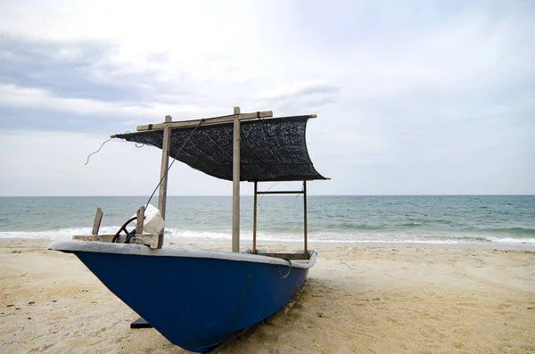 Fechado pescador barco encalhado na praia de areia e céu nublado — Fotografia de Stock