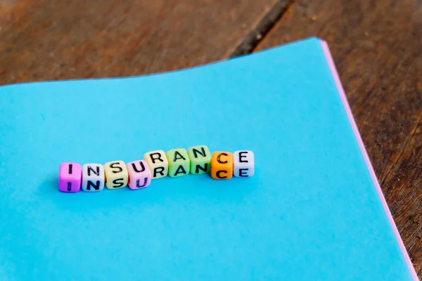 INSURANCE word block on note pad over wooden background