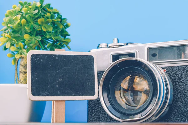 Image concept de voyage et de vacances, toile blanche avec chevalet, plante verte artificielle et disposition de la caméra vintage sur un bureau en bois — Photo
