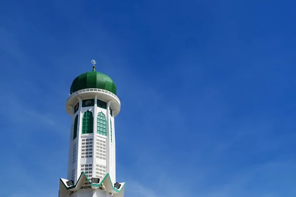 Башня мечети и зеленый купол на фоне голубого неба в солнечный день — стоковое фото