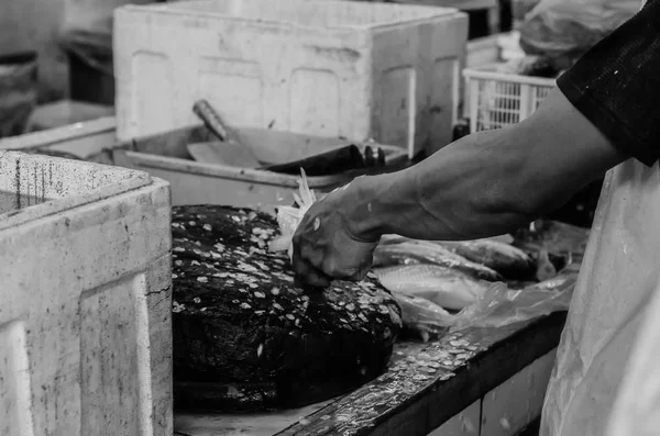 Black and white image of fresh market scene in Malaysia, fish monger clening his fish before selling activity.image may contain noise and grain — Stock Photo, Image