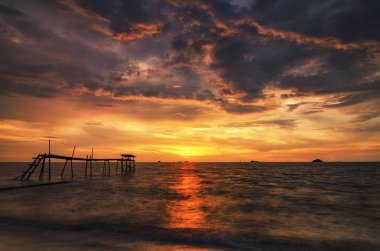 Sihirli altın günbatımı dramatik bulutlu gökyüzü ile sahilde.