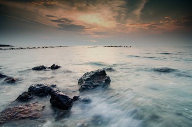 Muhteşem gün batımı an deniz manzarası, dalga yumuşak kaya üzerinde bulutlu gökyüzü isabet