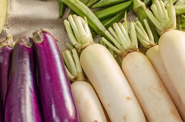 Berenjena morada cruda orgánica y exhibición de rábano blanco en el mercado local para la venta — Foto de Stock