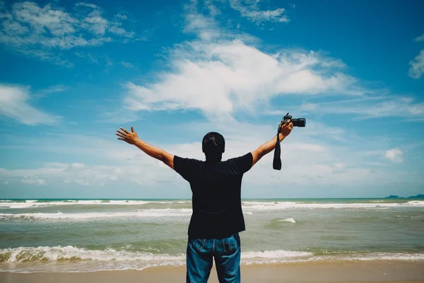 Jeune homme heureux non identifié et attrayant dans un t-shirt noir avec une caméra sur le fond de vue sur la mer — Photo