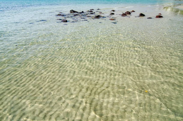 Beautiful sea water reflection and ripples on shallow sandy beach bottom of green lagoon at sunny day — Stock Photo, Image