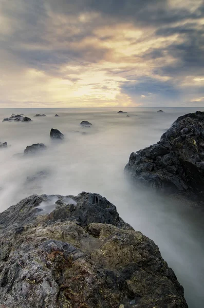 Hermoso y mágico momento de salida del sol cerca de la orilla del mar con el cielo nublado.suave ola golpeando la playa de arena . — Foto de Stock