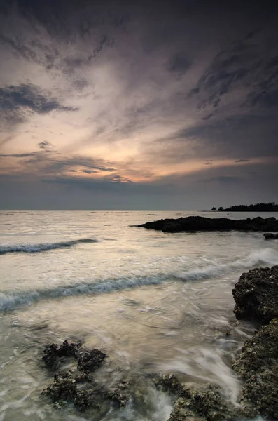 Όμορφη στιγμή ηλιοβασίλεμα στην παραλία με απαλό κύμα χτυπώντας τον βράχο και συννεφιασμένο ουρανό — Φωτογραφία Αρχείου