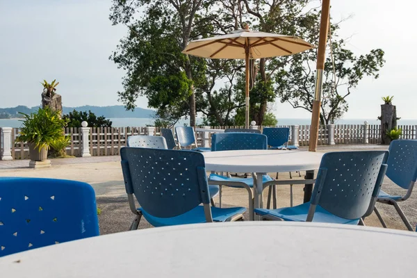 Masa ve sandalyeleri yakınındaki güzel tropikal deniz scape arka plan ile havuz yan kümesi