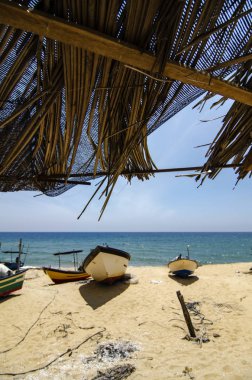 Bambu kulübe, ıssız kumsalda karaya geleneksel balıkçı tekne altında güzel sahne