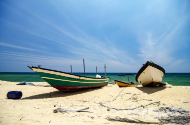  parlak güneşli bir günde altında ıssız kum plajındaki telli geleneksel balıkçı teknesi.