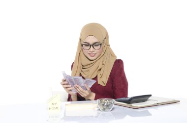 Gülümseyen iş yeri ve holding banknot üzerinde oturan gözlüklü genç ve güzel iş kadın portresi