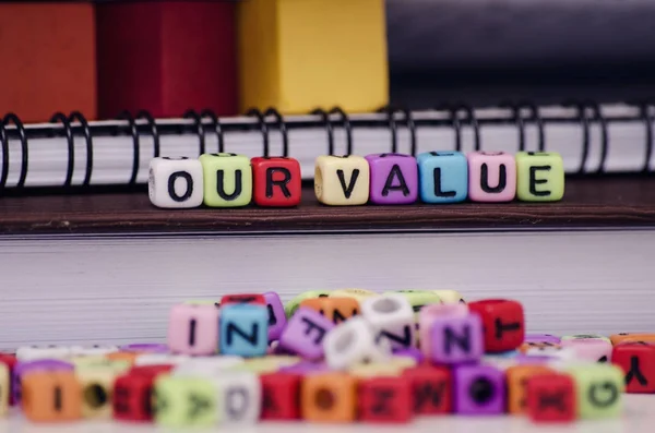 Cube dices with word OUR VALUE on note book. Selective focus and shallow depth of field — Stock Photo, Image