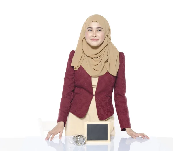 Glada ansikte vacker dam med hijab stående med tomma tavlan och mynt i burk på speglar bord — Stockfoto