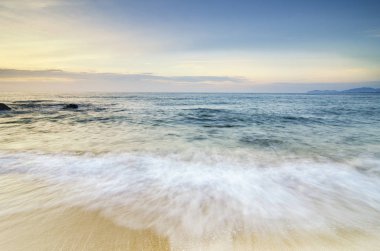 güzel tropikal plaj gündoğumu deniz manzarası. Dalga yumuşak isabet kumlu plaj