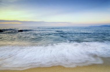 güzel tropikal plaj gündoğumu deniz manzarası. Dalga yumuşak isabet kumlu plaj