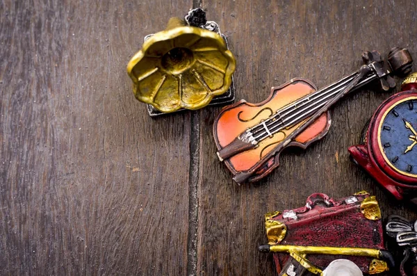 Miniature violin, clocks, travel bag and gramophone on wooden floor.text space on left — стоковое фото