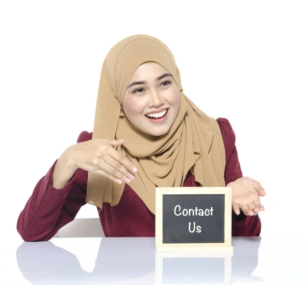 Поддержка бизнеса и услуги, улыбчивое лицо женщины, смотрящей на доску со словом CONTACT US — стоковое фото