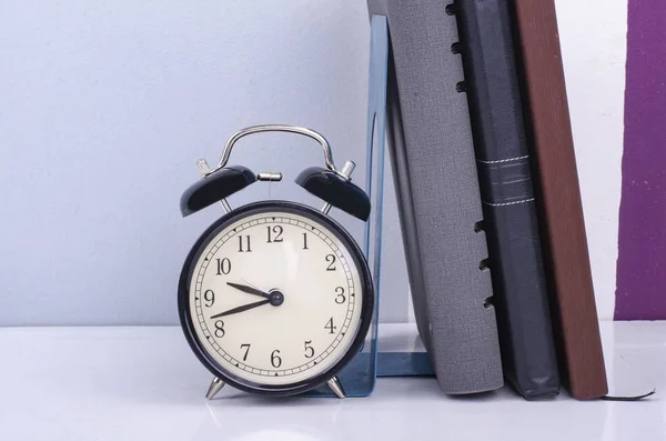 Vintage-Uhr und Tagebuch auf dem Tisch vor buntem Hintergrund Wand. — Stockfoto