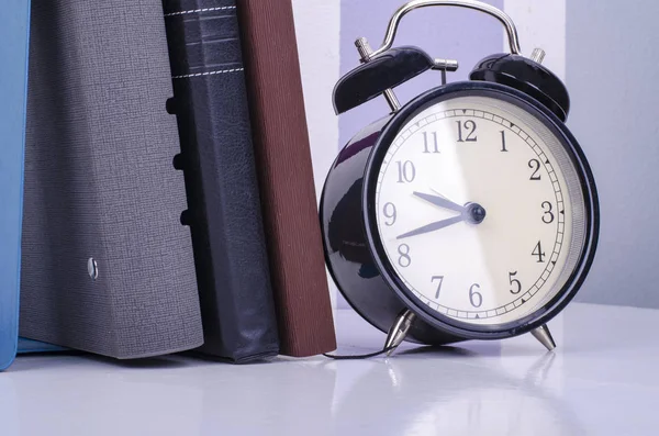 Vintage-Uhr und Tagebuch auf dem Tisch vor buntem Hintergrund Wand. — Stockfoto