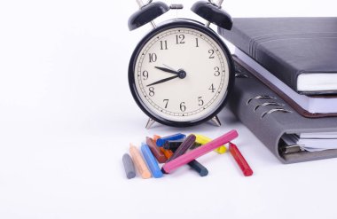 Vintage saat ve beyaz masa üzerinde renkli mum boya tik tak ile kitap yığını