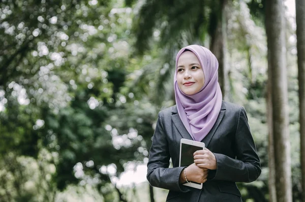 Sonriente joven profesional musulmana mujer de negocios sosteniendo una tableta en el parque — Foto de Stock