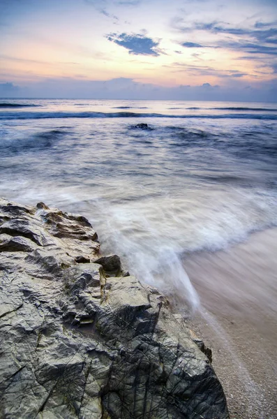 Ola suave golpeando roca en la playa de arena sobre el magnífico fondo del amanecer — Foto de Stock