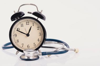 stayhealthy kavramı, stetoskop ve beyaz arka planda çalar saat