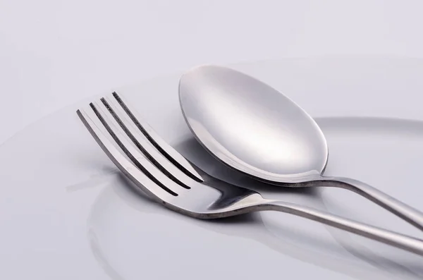 Tenedor y cuchara de plata en plato blanco — Foto de Stock