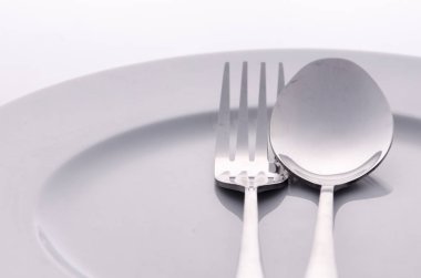 Beyaz plaka üzerinde gümüş kaşık ve çatal