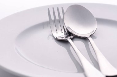 Beyaz plaka üzerinde gümüş kaşık ve çatal