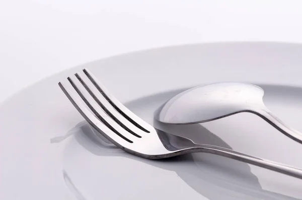 Tenedor y cuchara de plata en plato blanco — Foto de Stock