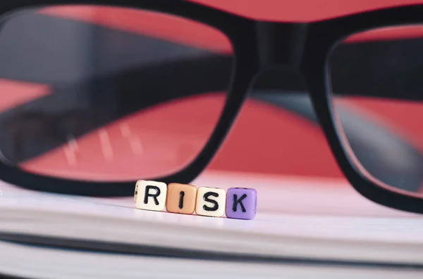 Kockázat menedzsment koncepciója. Kockázat szó kocka a könyv fölött piros háttér — Stock Fotó