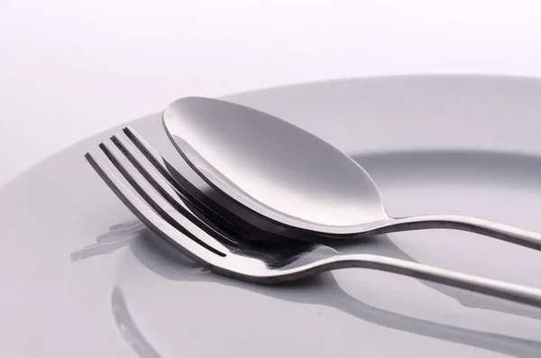 Tenedor y cuchara de plata en plato blanco — Foto de Stock