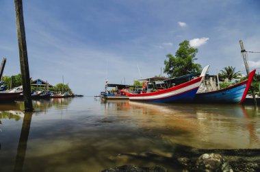 Güzel kırsal manzara, balıkçı teknesi ahşap iskelenin yanında demirlemiş mavi gökyüzü arkaplanı üzerinde