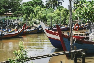 Güzel kırsal manzara, balıkçı teknesi ahşap iskelenin yanında demirlemiş mavi gökyüzü arkaplanı üzerinde