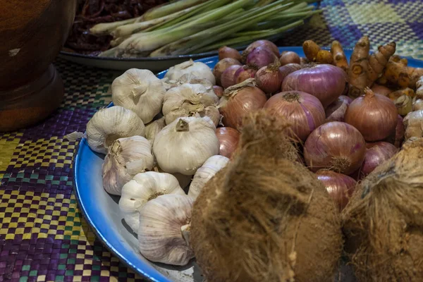 Состав разнообразных сырых продуктов питания, кокоса, лука, имбиря, чеснока и лимонной травы на традиционных малайских ковриках — стоковое фото