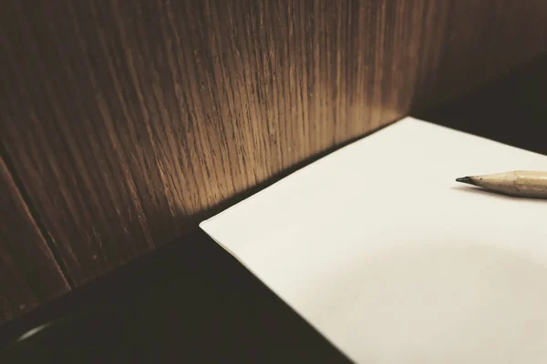 Pusta kartka papieru i pióra na biurku, drewniane tło o płytkiej głębi ostrości — Zdjęcie stockowe