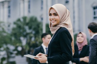 Siyah takım elbiseli mutlu iş kadını portresi ayakta ve elinde tabletle 