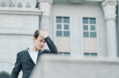 Hüsrana uğramış ve depresif yüz ifadesi, genç iş adamı sığ alan arka planının üzerinde duruyor