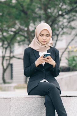 Mutsuz yüz ifadesi, genç muslimah oturuyor ve arkadaşına cep telefonu kullanıyor.