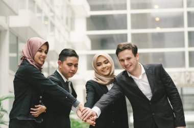 Birlikte çalışmak ya da takım çalışması. Takım elbiseli genç iş adamlarından oluşan bir grup el ele veriyor..