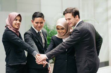 Birlikte çalışmak ya da takım çalışması. Takım elbiseli genç iş adamlarından oluşan bir grup el ele veriyor..
