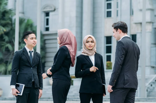 Group of young executive people in formalwear discussing something and gesturing