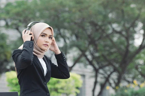 Porträtt av vacker kvinna i svart kostym och hijab leende lyssna på musik — Stockfoto
