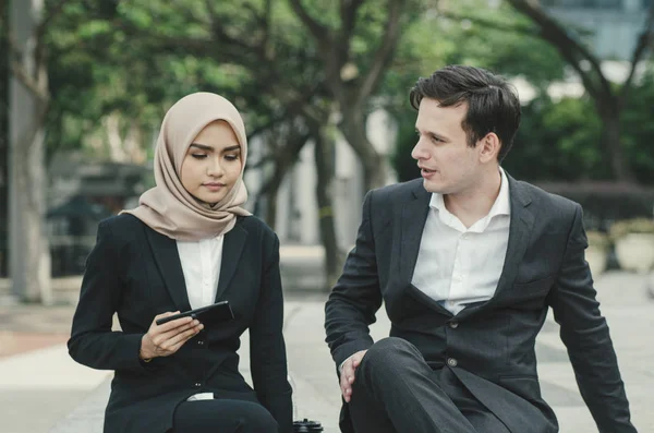 young business couple in formalwear siiting outside and having discussion