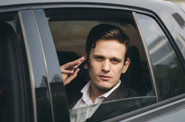 Портрет молодого бизнесмена, разговаривающего с кем-то по мобильному телефону с серьезным выражением лица . — стоковое фото