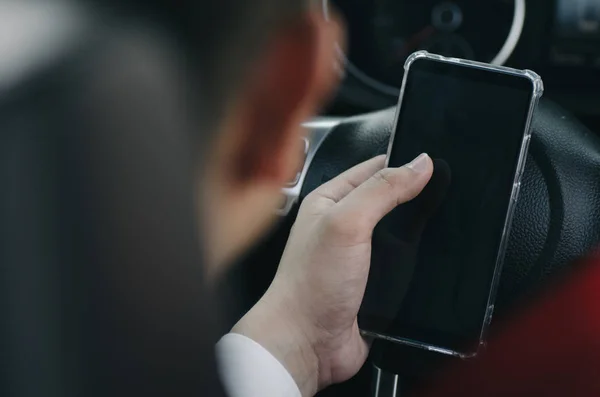 Крупный план молодого бизнесмена, держащего свой смартфон в машине — стоковое фото