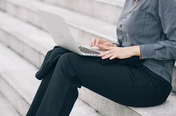 unidentified young executive sitting on stars and work with her laptop