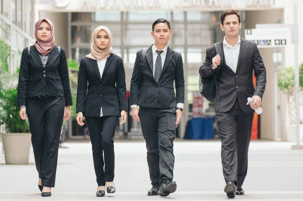 Des gens d'affaires jeunes et confiants marchant ensemble dans un couloir de bureau moderne — Photo